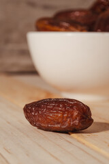 Dates Fruit in a Ceramic Bowl on a Wooden Table..