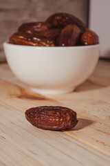 Dates Fruit in a Ceramic Bowl on a Wooden Table..
