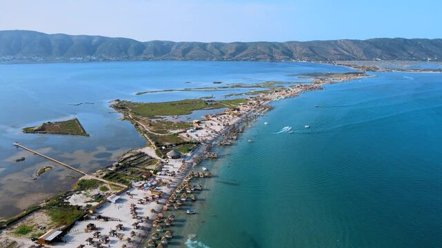 An aerial perspective of Ghar El Meleh's coastal landscape in Bizerte. The image highlights the beach's unique features, including straw huts, boats, and the surrounding wetlands.