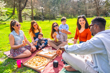 Happy families eating pizza and enjoying a picnic in a park