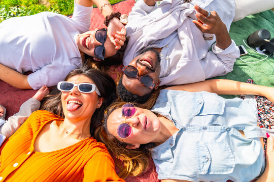 Happy multi ethnic friends taking funny selfie at park picnic - Powered by Adobe
