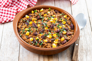 Traditional Mexican Chili con carne. Minced meat and vegetables stew in tomato sauce on wooden table