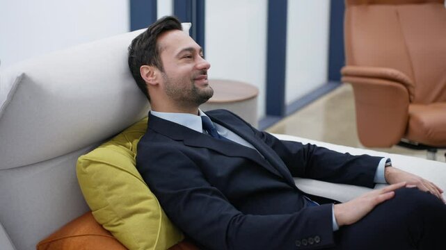 Successful Businessman checking mobile phone relaxing on a couch in a positive mood with a satisfactory smile and confidence