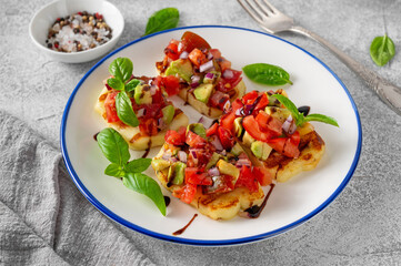 Grilled halloumi cheese with tomatoes, avocado, onion and balsamic sauce on a plate on a concrete background.