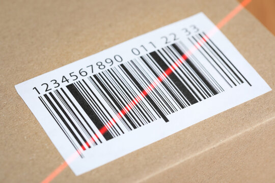 Parcel with label, closeup. Red laser light on barcode for scanning