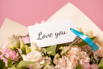 romantic bouquet of pastel flowers with a handwritten love you message card tied with a blue...