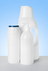 Bottles of cleaning products on white table against light blue gradient background