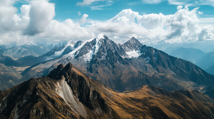 An aerial perspective of a mountain range featuring snow-capped summits and a vast natural setting