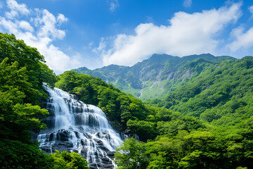 Fototapeta premium Lush green mountains frame a cascading waterfall under a vibrant blue sky
