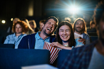 Couple laughing while watching comedy movie at cinema