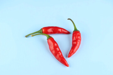Three red hot chili peppers on white surface