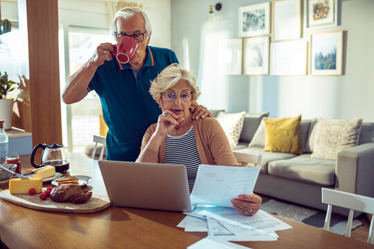 Senior couple managing finances and bills at home with laptop