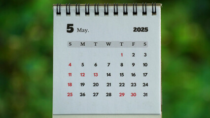 Desk Calendar Displaying May 2025 with Green Nature Bokeh Background for Planning and Scheduling
