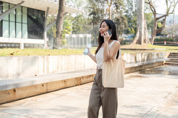 Fototapeta premium Sustainable lifestyle in motion. Young woman walking with a phone and water bottle, embracing a sustainable lifestyle.