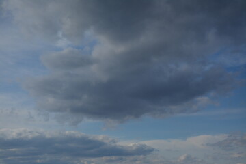 Grey clouds hung over the blue sky

