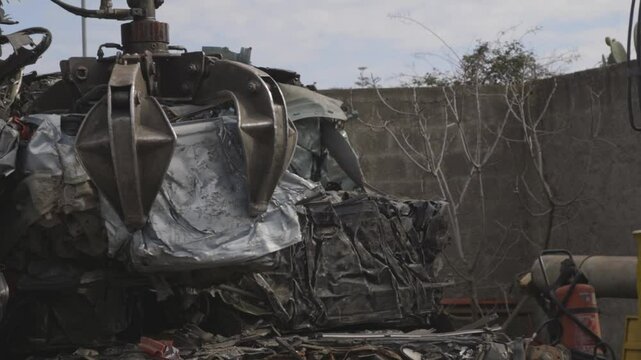 braccio meccanico solleva un'auto demolita in uno sfasciacarrozze