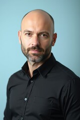 Fototapeta premium Portrait of confident bald businessman posing on blue background