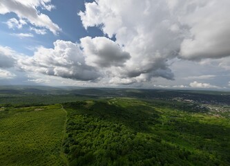 Aerial view of a green valley with agricultural plantations and dense clouds
