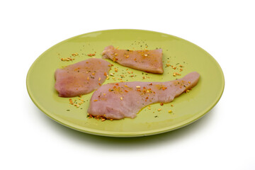 Three pieces of fresh - raw chicken on a green plate salted with dry vegetable seasoning. Fresh chicken meat ready for grilling or pan-frying. Raw chicken meat. Clipping path included.