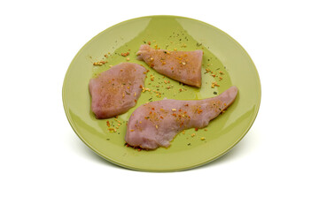 Three pieces of fresh - raw chicken on a green plate salted with dry vegetable seasoning. Fresh chicken meat ready for grilling or pan-frying. Raw chicken meat. Clipping path included.