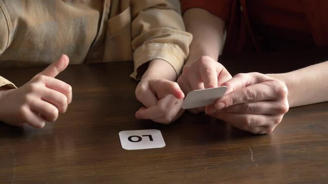 mother teaches her young son to speak using flashcards in the living room at home.