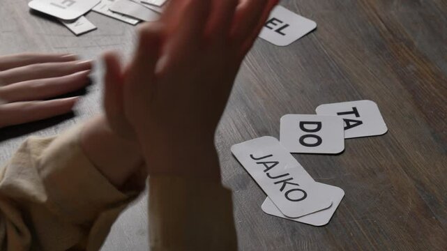 mother teaches her young son to speak using flashcards in the living room at home.