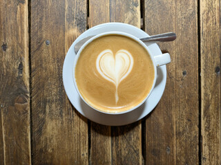Close Up of an Oat Milk Latte Coffee in White Cup on a Rustic Wooden Table Background with Love Heart