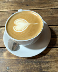 Close Up of an Oat Milk Latte Coffee in White Cup on a Rustic Wooden Table Background with Love Heart