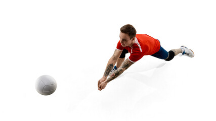 Top view image of concentrated male volleyball player reaching towards ball, training, playing against white studio background. Concept of sport, competition, energy, active lifestyle, determination.
