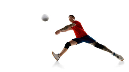 Naklejka premium Low angle view of focused man, volleyball player in motion, hitting ball, playing against white studio background. Concept of sport, competition, energy, strength, active lifestyle, determination.