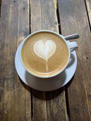 Close Up of an Oat Milk Latte Coffee in White Cup on a Rustic Wooden Table Background with Love Heart