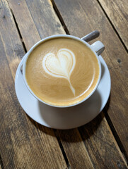 Close Up of an Oat Milk Latte Coffee in White Cup on a Rustic Wooden Table Background with Love Heart