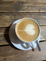 Close Up of an Oat Milk Latte Coffee in White Cup on a Rustic Wooden Table Background with Love Heart
