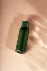 Beautiful cosmetic green jar and petri dishes in sunlight rays shadow falling on background. Cosmetic background. Flat lay style.