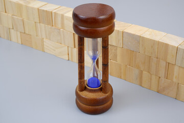 Wooden cubes wall and hourglass on gray background.