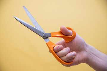 hand holding pair of scissors on yellow background