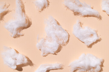 Delicate fluffy pieces of cotton wool on light background, top view. Cotton clouds, natural eco-friendly material for hygiene, medicine, health, fabric manufacturing
