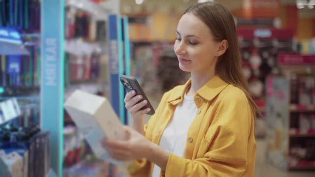 In a vibrant retail store, a shopper in a yellow jacket uses her smartphone to scan items while standing in front of a colorful display of products.