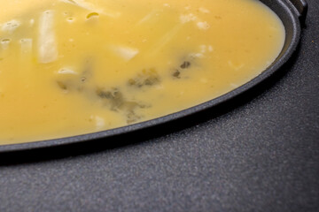 Beaten eggs and cheese in an omelet cooker