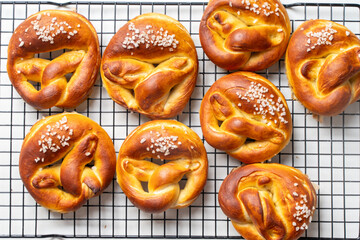 Appetizing pretzels or buns with coarse salt on a black grill on a white background. Top view. Close up. Flat lay