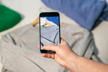 Woman taking photo of used clothes in good quality. Preparing to sell in second hand online market....