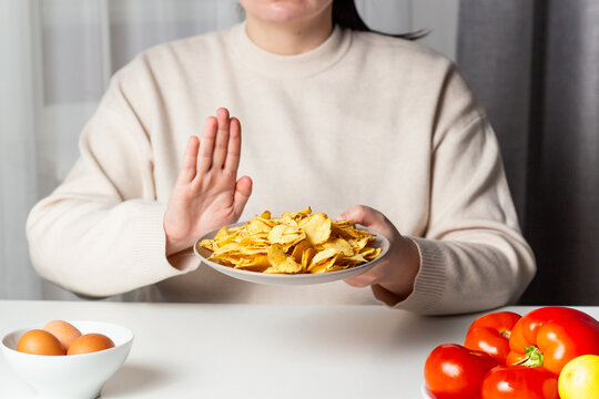 Closeup of woman making stop sign to refuse fried chips for dieting and healthy eating. Vegetable plate. Weight loss concept.