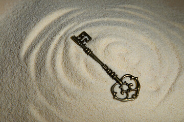 vintage key lies on the sand. The concept of time as sand