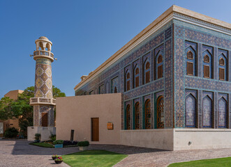 View of ornate architectural building with tower and minaret featuring vibrant mosaic tiles, Al Souq, Doha, Qatar.