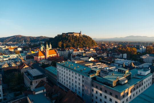 Fototapeta View of ljubljana castle and saint nicholas's cathedral at sunset with picturesque rooftops and hills, ljubljana, slovenia.