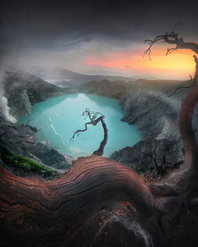 View of Ijen crater lake surrounded by majestic mountains and vibrant trees at sunrise, Licin, East Java, Indonesia.
