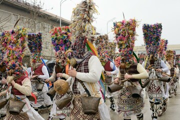 Bulgarian Kukeri with Rooster Skin, Feathers, Ribbons and Horse Tail  accent Masks and Bells