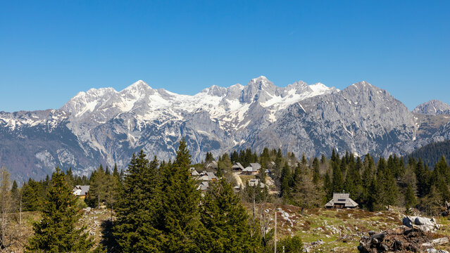View of summer mountain landscape with hut village and majestic peaks Grintovec, Skuta, and Planjava, Velika Planina, Kamnik, Slovenia.