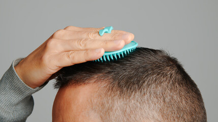 man uses a round scalp brush to comb his hair