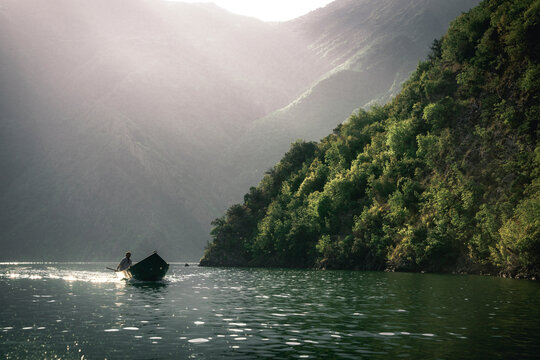 Shkoder, Albania - 10 March 2025: View of tranquil Koman Lake surrounded by majestic mountains and lush forest, Shkoder, Albania.